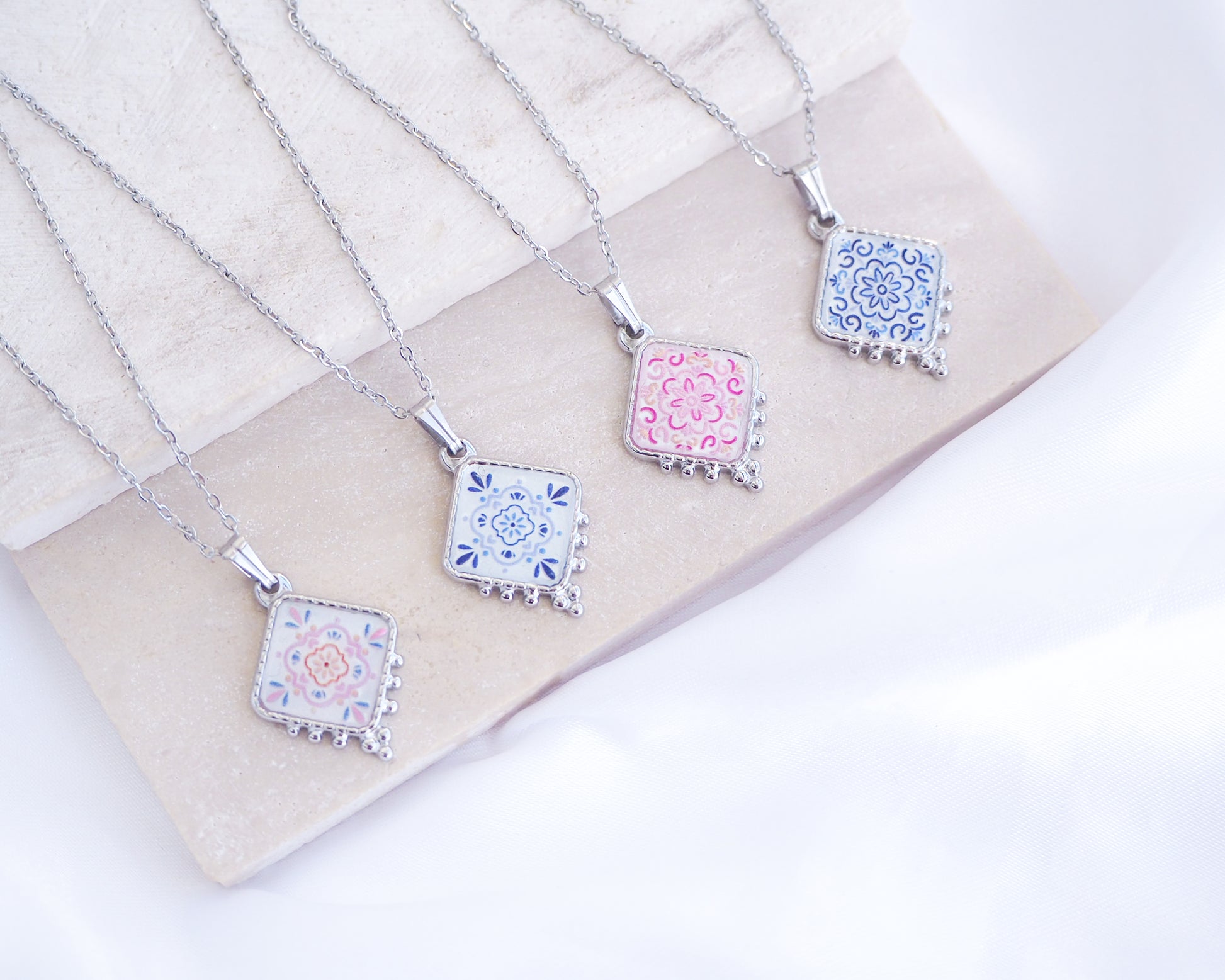 Portuguese Tile Necklace Floral Blue Silver on stone displayed. Made with silver stainless steel and white blue floral and pink floral pendant inspired by the Portuguese Azulejo design pattern. 