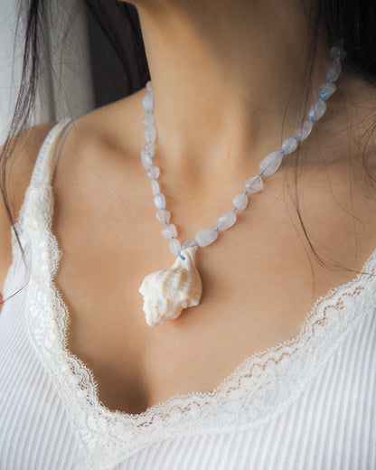 Model wearing Big white Murex Shell Necklace with Aquamarine Gemstone Beads on neck, Blue gemstone bead necklace with off white big conch shell, Handpicked Banded Dye-murex shell from Portugal