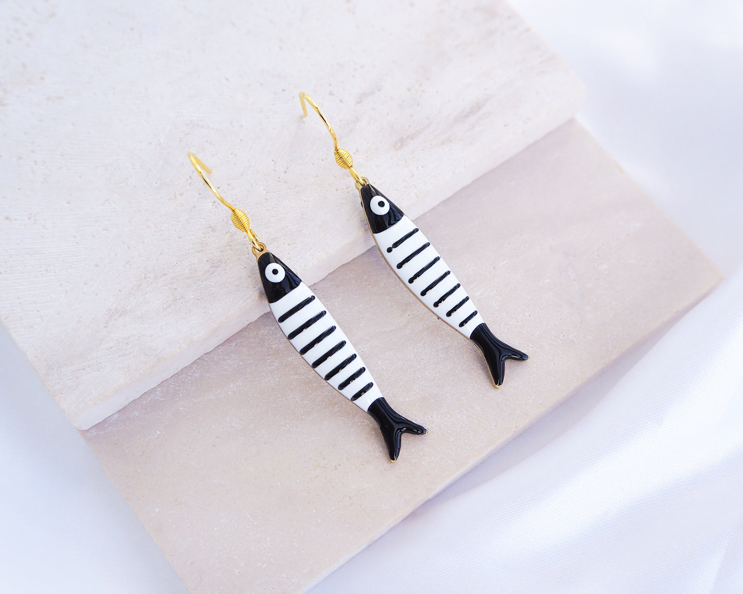 Black and White Striped Sardine Fish Earrings with 14k gold stainless steel earring hooks displayed on stone, Nautical Striped Fish Pendant, Beautiful gift for Portugal lovers or holiday memory, coastal jewelry from Portugal