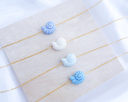 Blue Ceramic Seashell Nautilus Gold Necklaces all displayed on stone