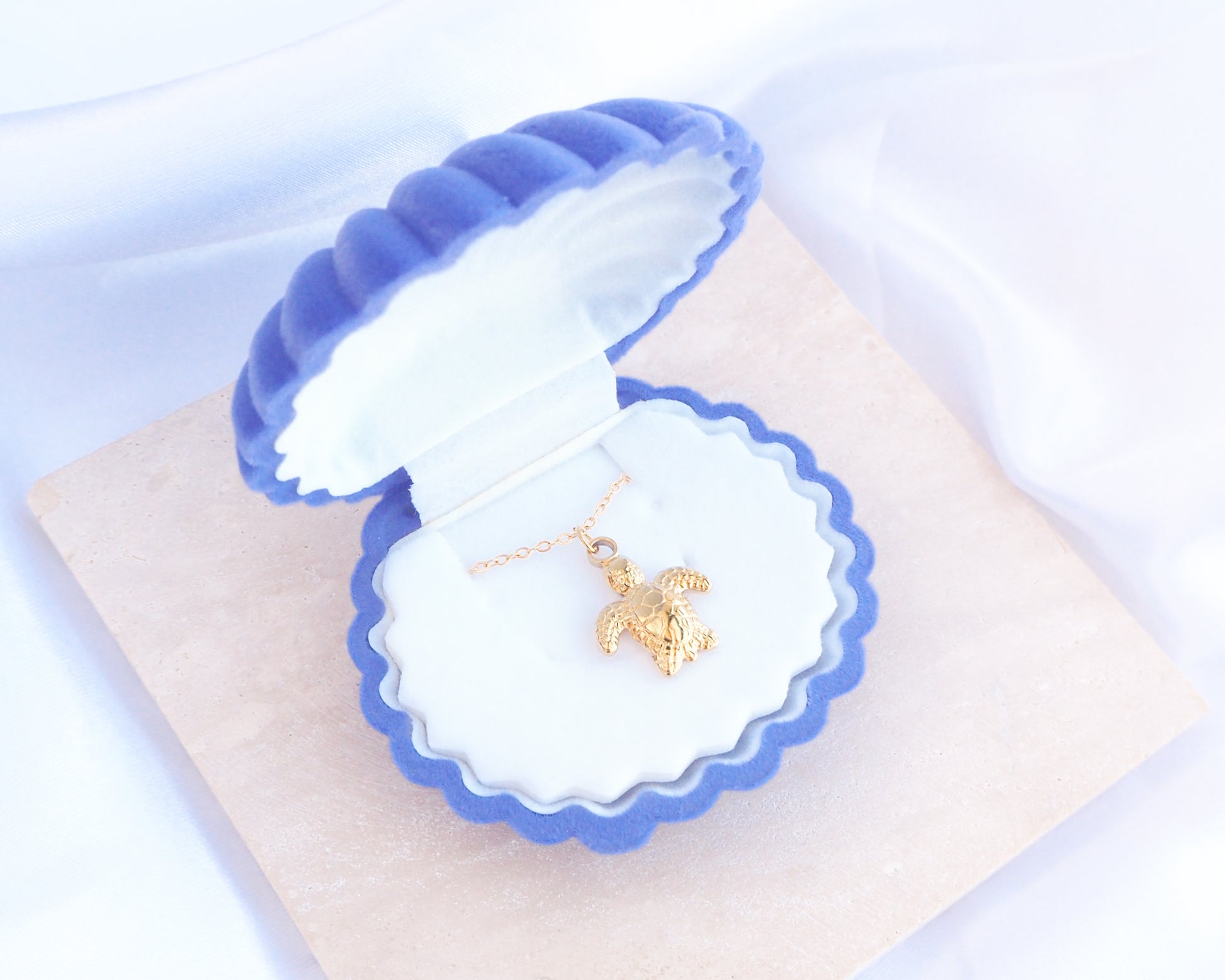 Blue Velvet Seashell Jewelry Box with Gold Baby Turtle Necklace, Shell shaped jewelry box blue velvet seashell jewellery box on stone displayed 