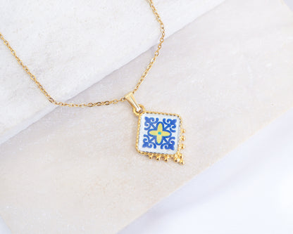 Close up of Blue Yellow Portuguese Tile Necklace Gold on stone displayed. Made with 18k gold stainless steel and blue yellow purple pendant inspired by the Portuguese Azulejo design pattern. 