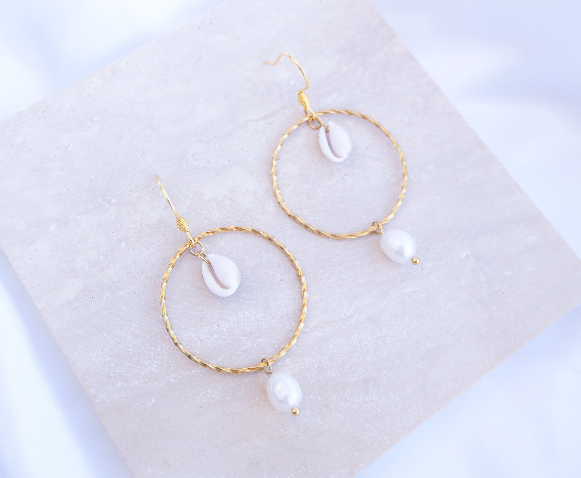 Boho Chic Cowrie Shells Pearl Hoop Earrings on stone displayed, 18k Gold Stainless Steel Hoop earrings with tiny cowrie shells handpicked from Portugal. Conchas Beijinhos, Ivory freshwater pearls, seabylou 
