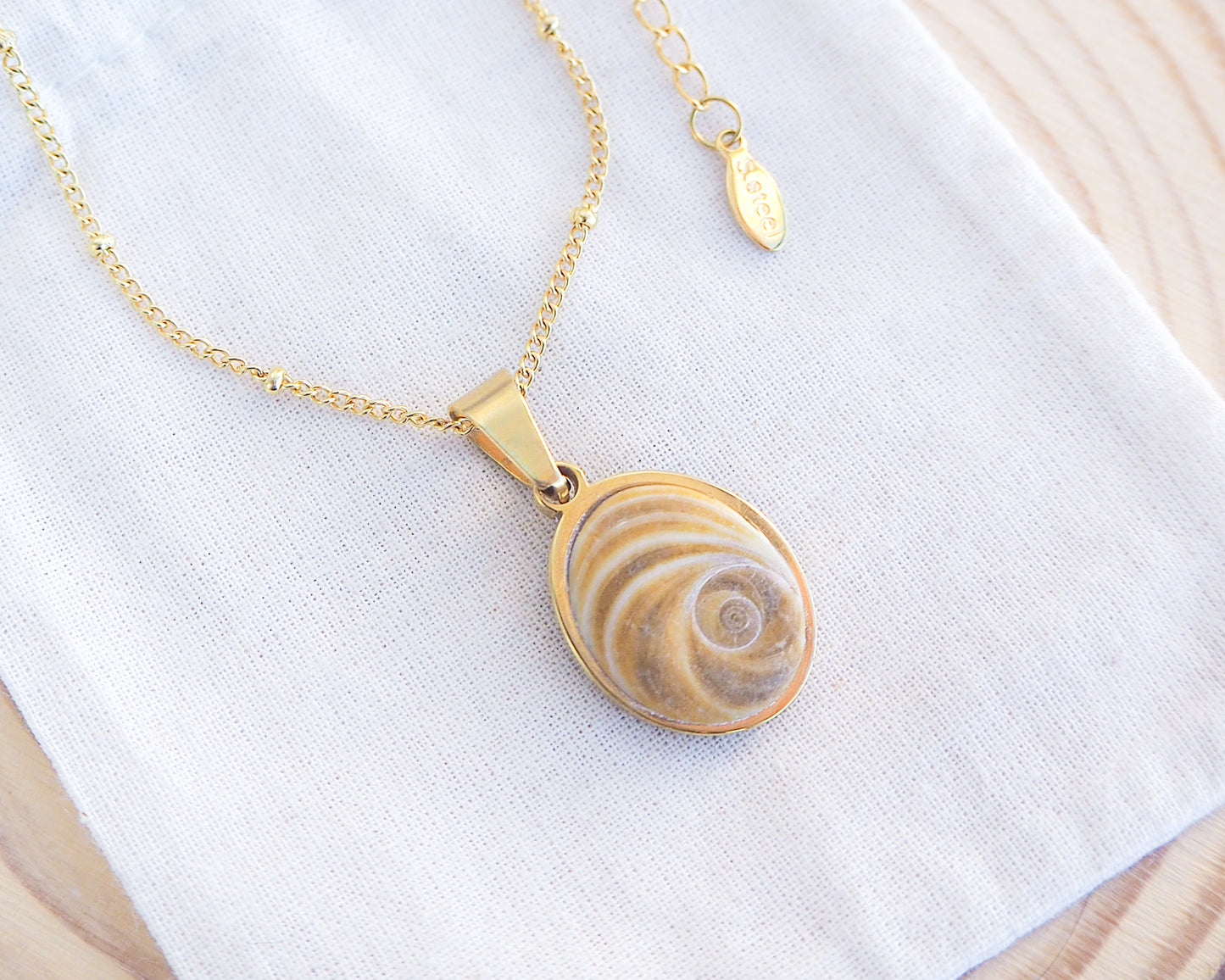 Brown Eye of Saint Lucia Gold Necklace on cotton displayed, 18k gold stainless steel brown shiva eye pendant necklace, Saint Lucy Eye, operculum pendant