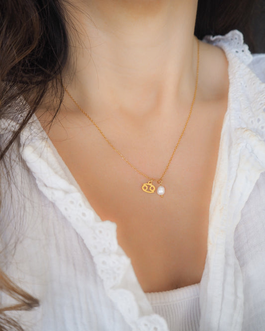 Model wearing Gold Cancer Zodiac Pearl Necklace on neck, made with 18k gold stainless steel and white freshwater pearl 