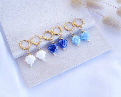 Ceramic Shell Gold Earrings with blue or white shell pendants on display