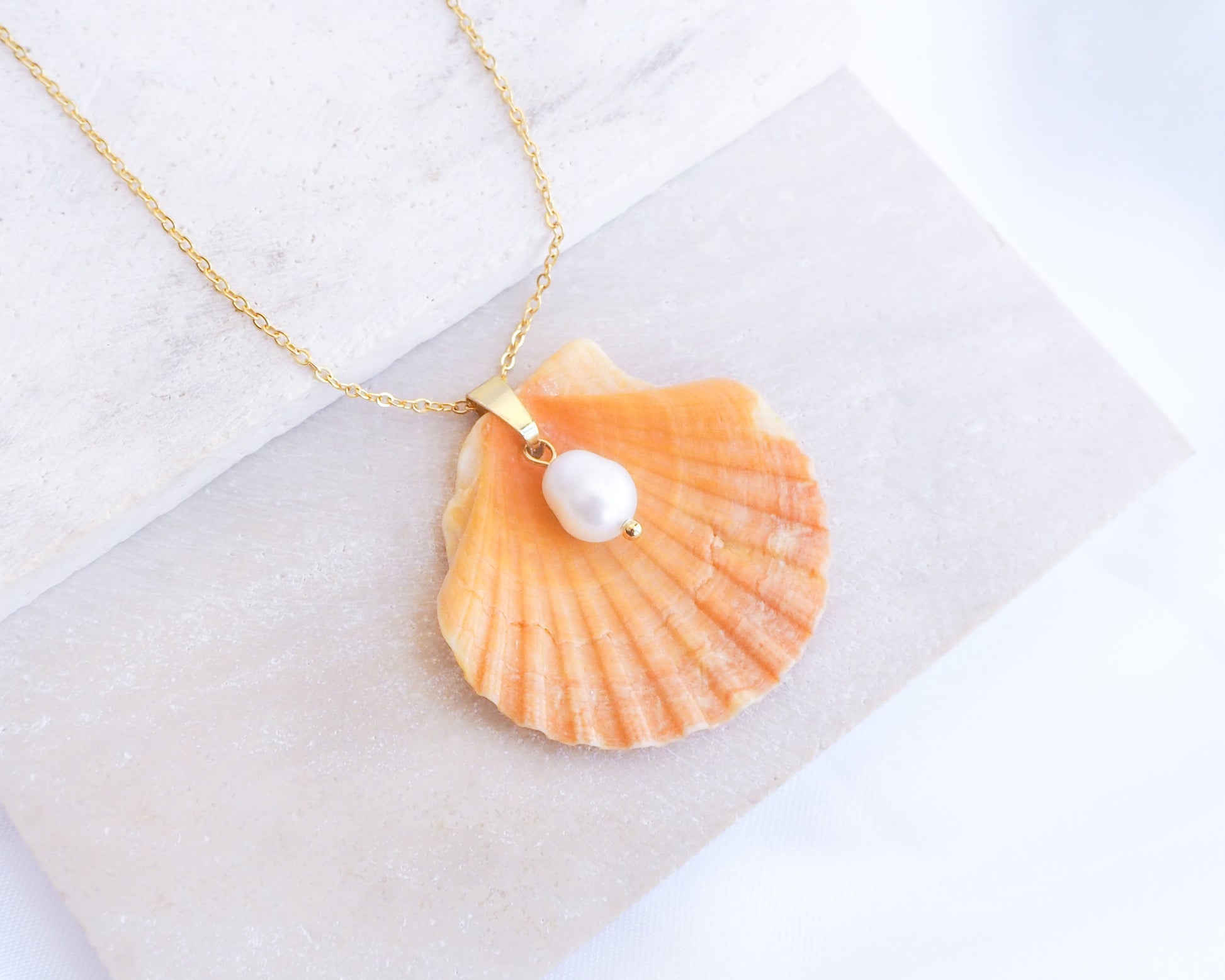 Coral Orange Scallop Shell Pearl Gold Necklace II on stone displayed, Pilgrims Scallop Shell from Portugal with freshwater pearl and gold chain.