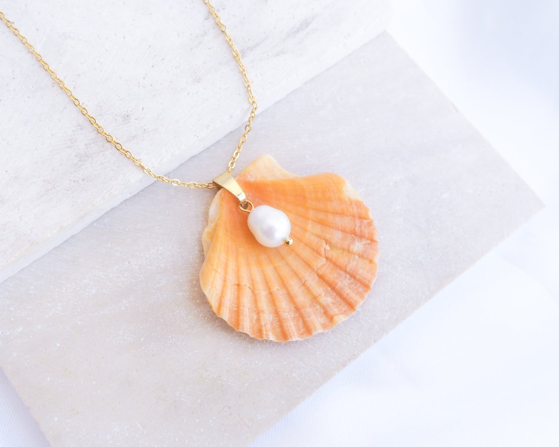 Coral Orange Scallop Shell Pearl Gold Necklace II on stone displayed, Pilgrims Scallop Shell from Portugal with freshwater pearl and gold chain.