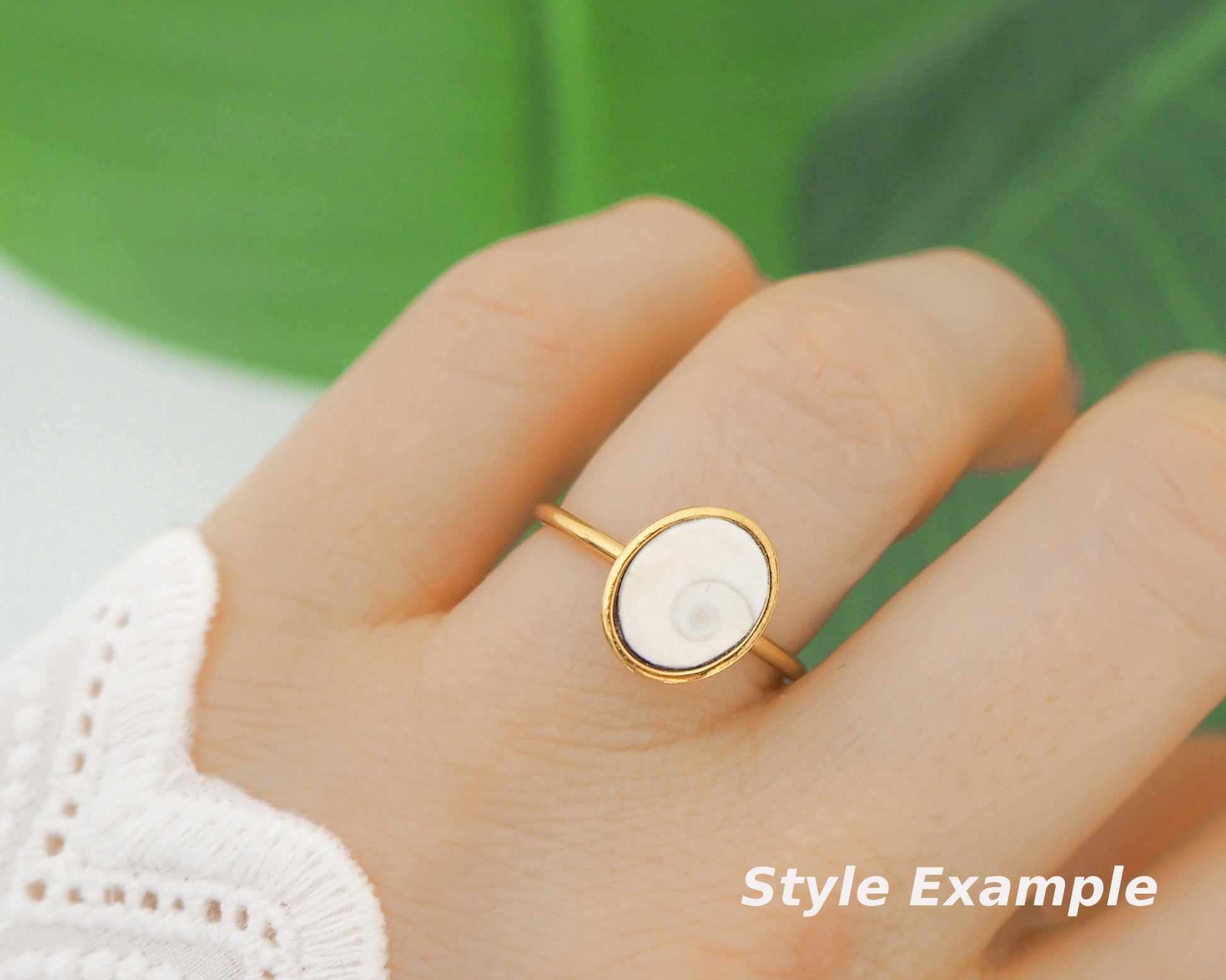 close up of finger with gold bezel ring with a ivory shiva eye. White Eye of Saint Lucia Gold Ring on stone displayed, 18k gold stainless steel shiva eye operculum, Saint Lucy Eye, operculum pendant