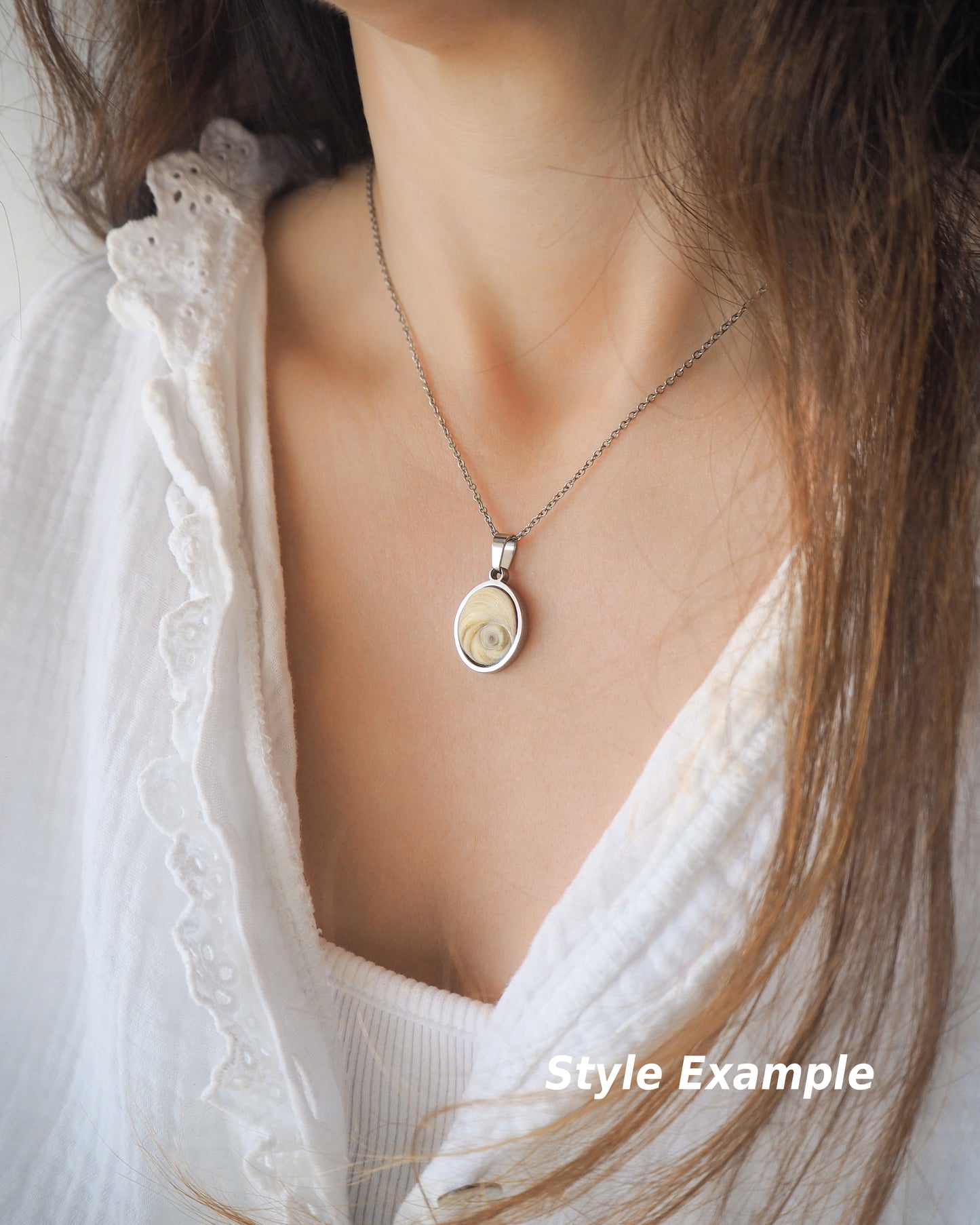 Model wearing Eye of Saint Lucia Silver Necklace on neck with white blouse and brown hair, silver stainless steel shiva eye pendant necklace, Saint Lucy Eye, operculum pendant