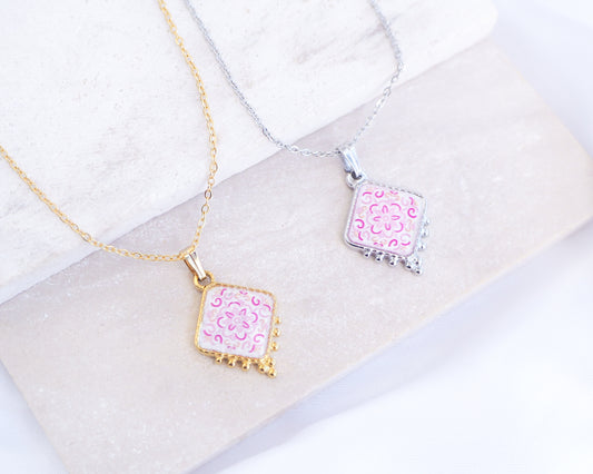 Close up of Portuguese Tile Necklaces Floral Pink on stone displayed. Made with 18k gold stainless steel and silver stainless steel. Showcasing white pink floral pendant inspired by the Portuguese Azulejo design pattern. 