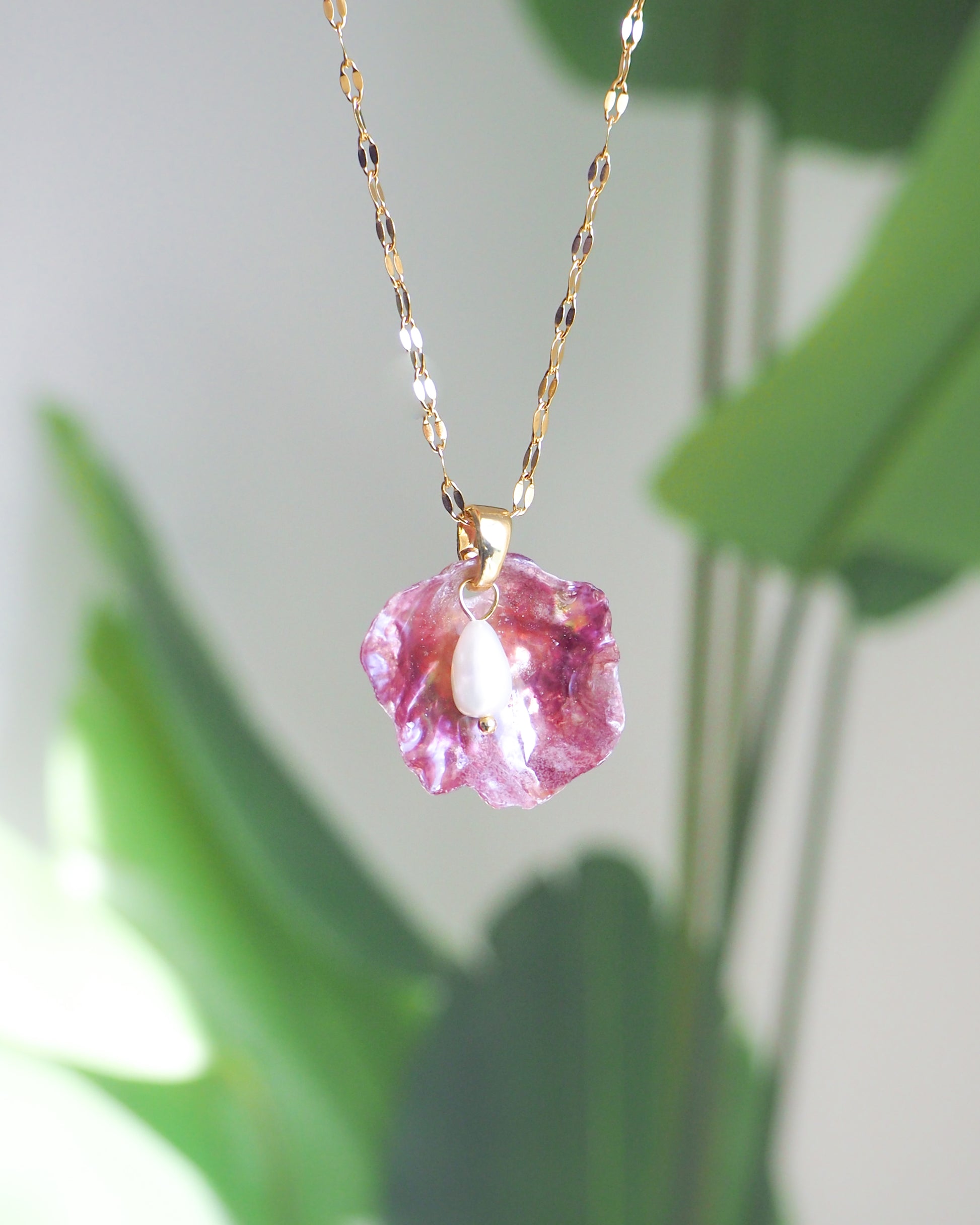 Front view of Fuchsia Pink Pearl Shell Necklace with green plant background 