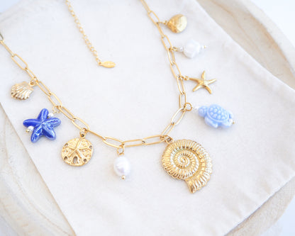Close up of Blue Ocean Ceramic Charm Necklace with 3 blue ceramic charms (turtle, starfish, shell), Shell pendant, sand dollar pendant, starfish pendant, 18k gold stainless steel chain on display 