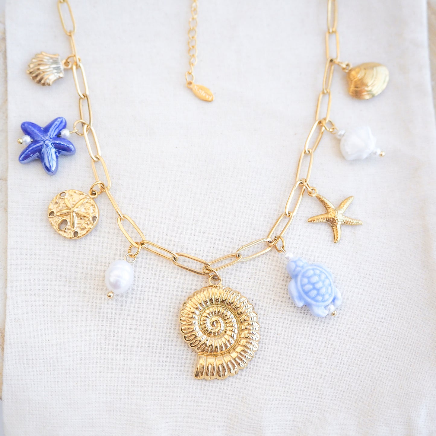 Front view of Blue Ocean Ceramic Charm Necklace with 3 blue ceramic charms (turtle, starfish, shell), Shell pendant, sand dollar pendant, starfish pendant, 18k gold stainless steel chain  