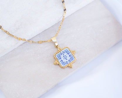 Close up of Blue Floral Portuguese Tile Square Necklaces Blue on stone displayed. Made with 18k gold stainless steel and white blue mosaic pendant inspired by the Portuguese Azulejo design pattern. 