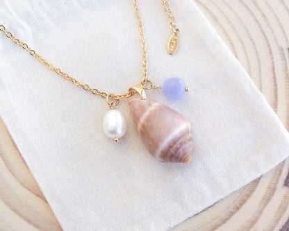Close up of gold necklace with real cone shell and a gemstone and pearl necklace on display. Mediterranean cone shell was handpicked from Portugal. Made with a ivory white freshwater pearl and blue angelite gemstone bead. Made with 18k gold stainless steel clasp and necklace chain. 