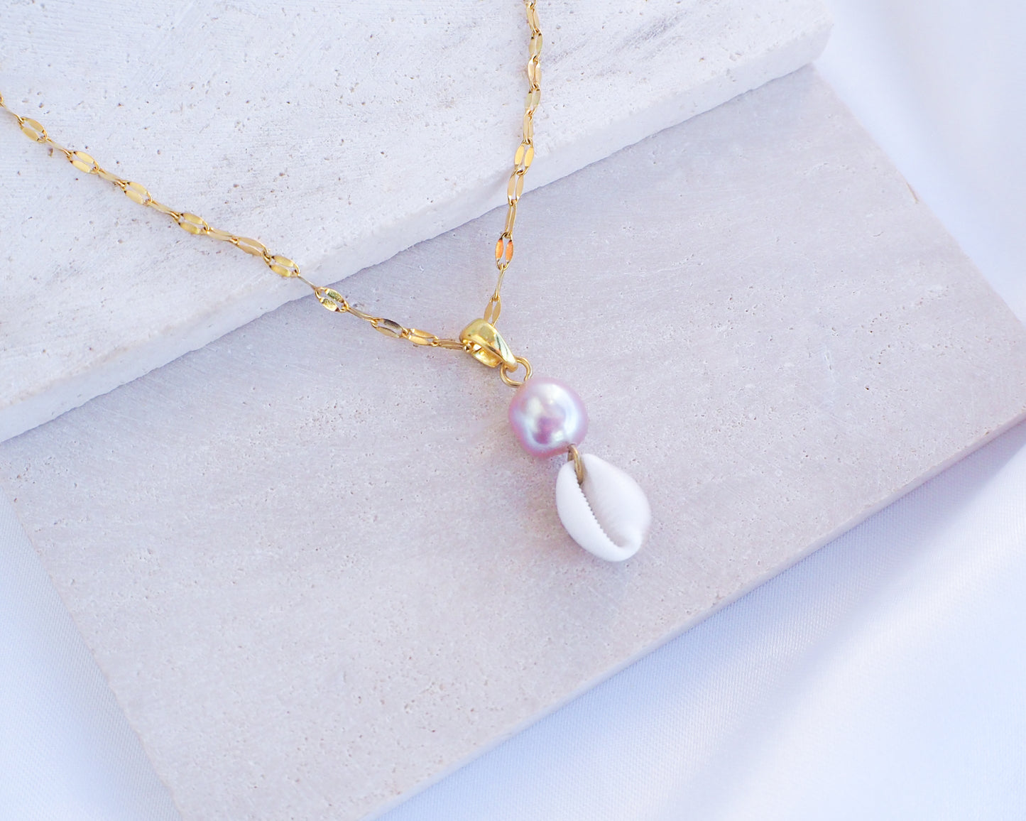Deluxe Gold Necklace with Tiny Cowrie Shell from Portugal and a Pink Rose Pearl on display