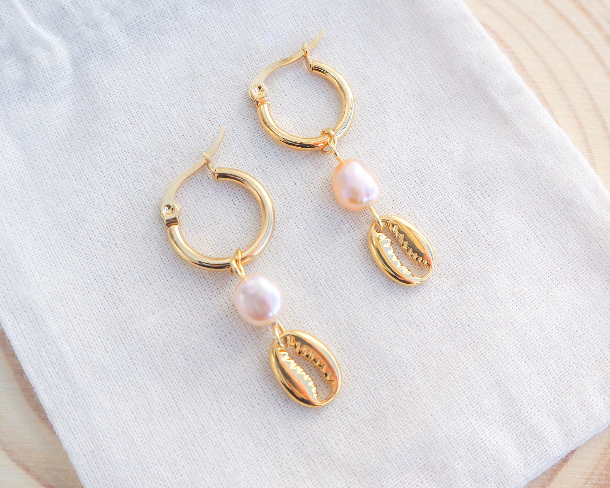 Gold Hoop Earrings with Cowrie Shells and Pearls on display