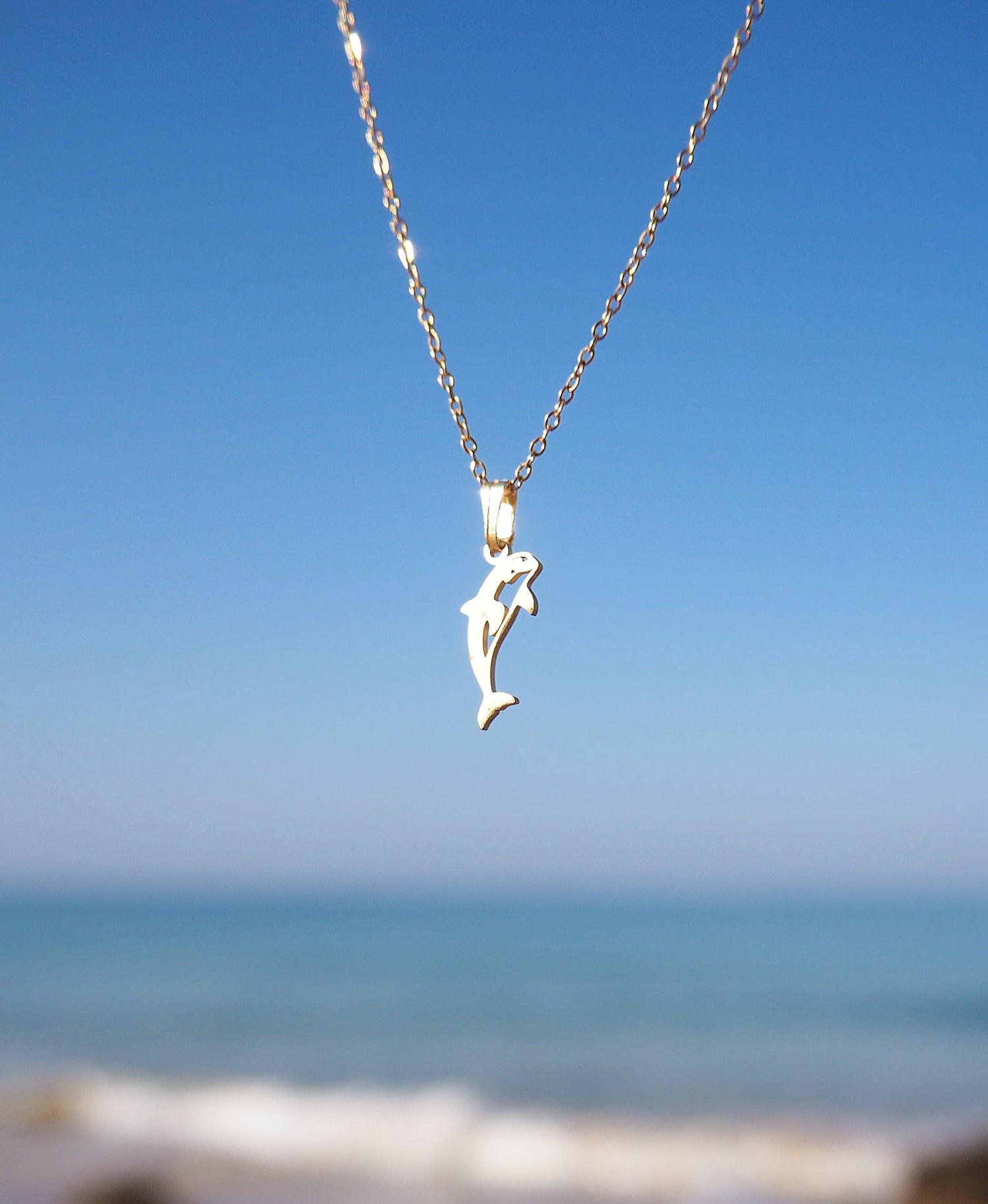 Gold Orca Killer Whale Necklace with ocean view background 