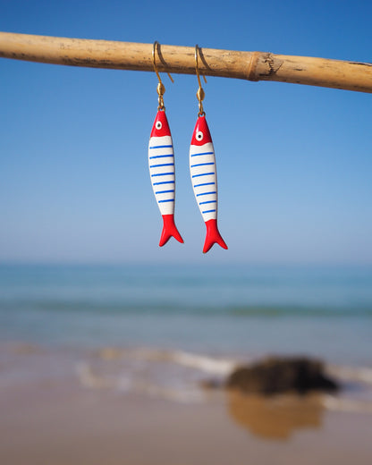 Close up of Nautical Striped Sardine Fish Earrings with ocean background, Red Blue White Striped Fish Pendant, Beautiful gift for Portugal lovers or holiday memory, coastal jewelry from Portugal