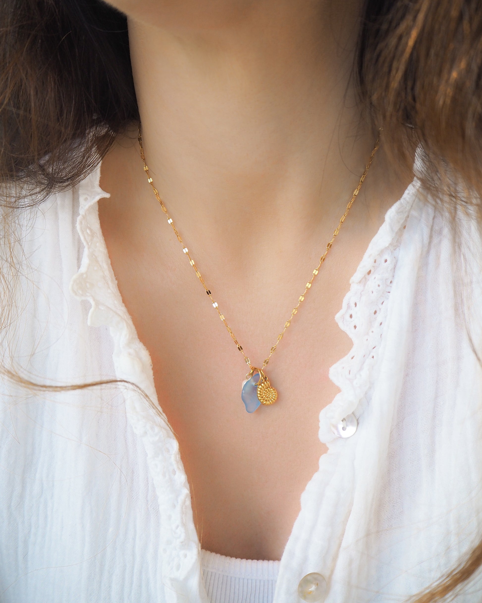 Model wearing Oceanic Trio Nautilus Blue Sea Glass Pearl Necklace on neck, nautilus shell necklace, ocean blue necklace, coastal jewelry, freshwater pearl necklace, gold seashell necklace, ocean-inspired jewelry, beach necklace, ocean treasure necklace