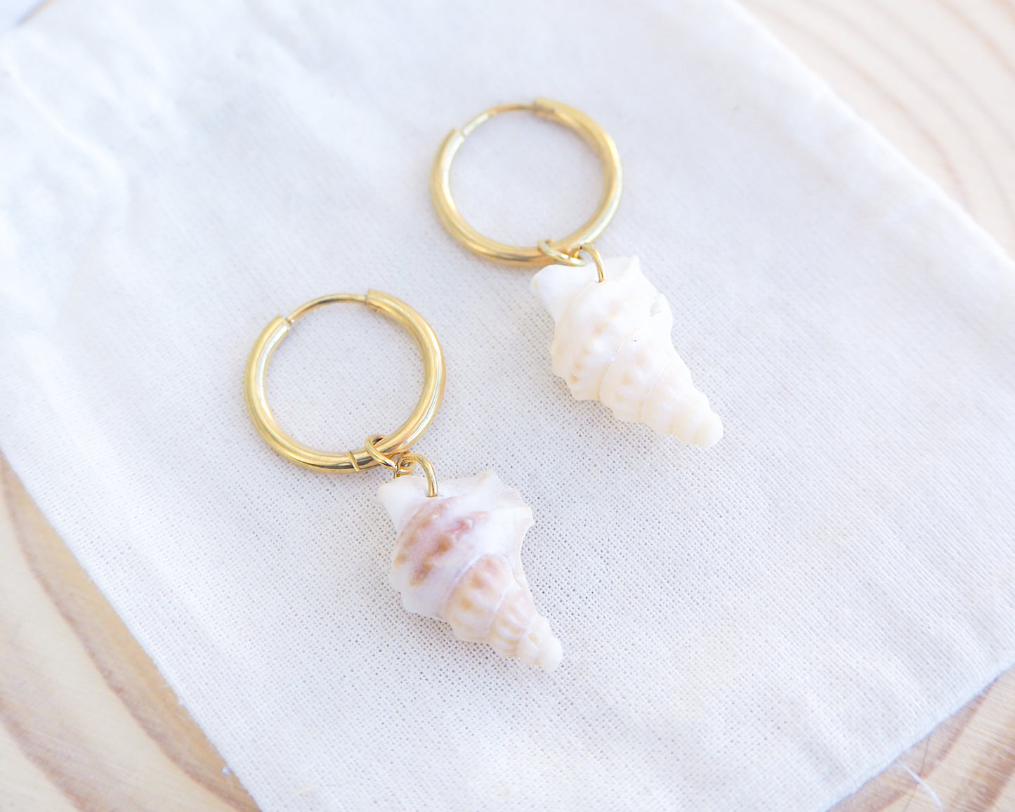 Pelicans Foot Shell Gold Earring Hoops displayed on display, handpicked white pelican foot shells from Portugal, 18k gold stainless steel shell earring hoops, seabylou 