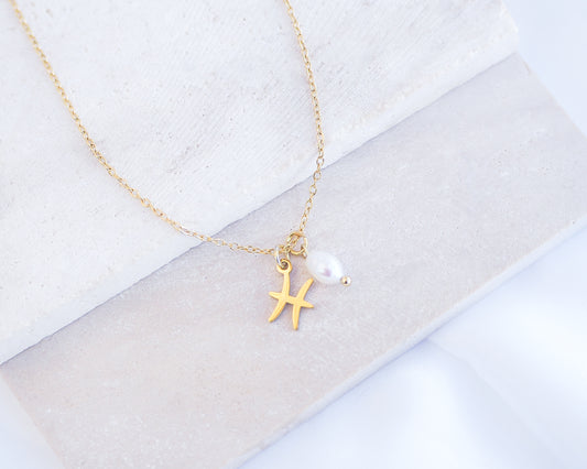 Gold Pisces Zodiac Pearl Necklace on stone displayed, made with 18k gold stainless steel and white freshwater pearl 