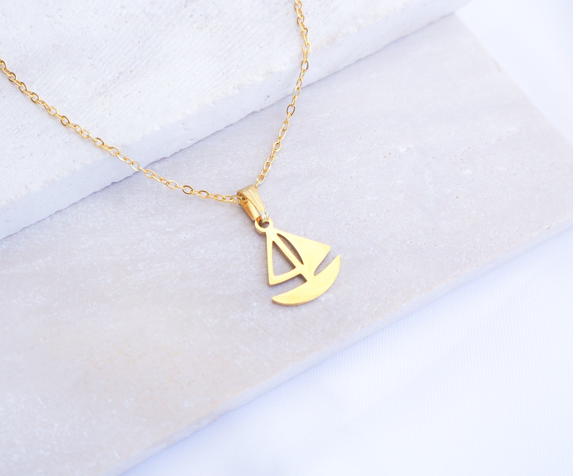 Gold Sailing Boat Necklace made with 14k gold stainless steel on display
