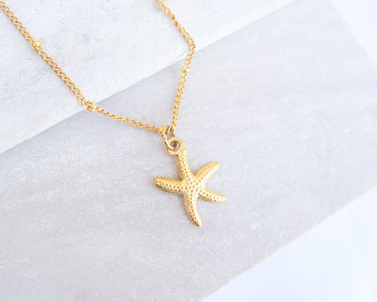 Gold starfish sea star necklace on a white background