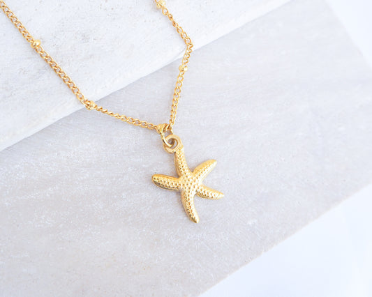 Gold starfish sea star necklace on a white background