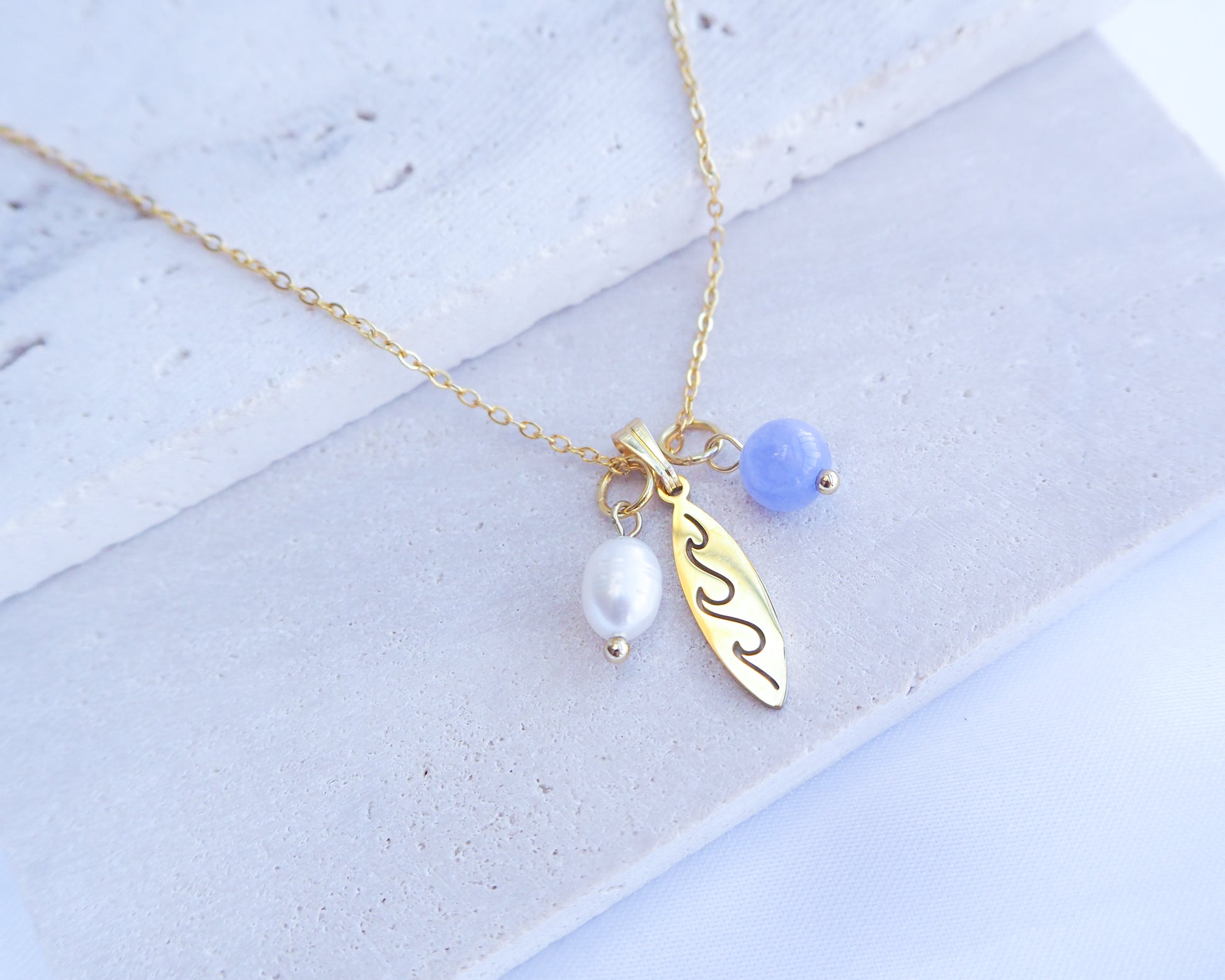 Gold Surfboard Necklace with Freshwater Pearl Angelite Beads on display