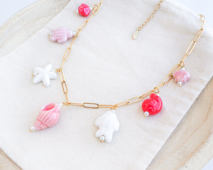 Side view of Sweet Ocean Ceramic Charm Necklace with 7 ceramic ocean charms (turtle, starfish, fish, shell & more), Pink white red sea pendants, 18k gold stainless steel chain displayed