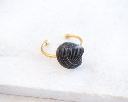 Side view of Tiny Black Venus Shell Gold Ring displayed on stone, Handpicked real black venus shell from Portugal, adjustable 18k gold stainless steel shell ring