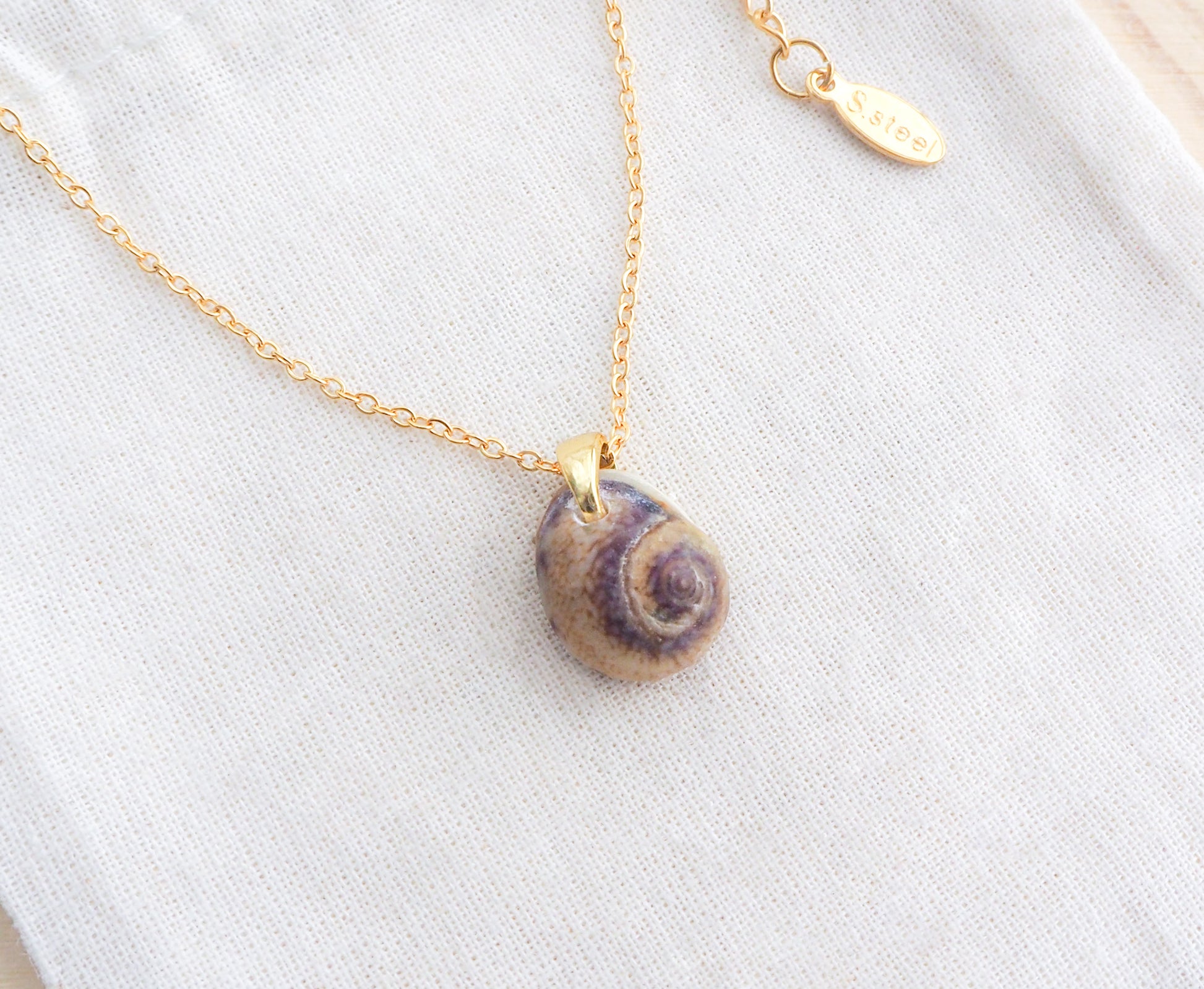 Gold Tritia Neritea Shell Necklace II displayed on stone, handpicked tritia neritea shell from Portugal, 18k gold stainless steel necklace chain 