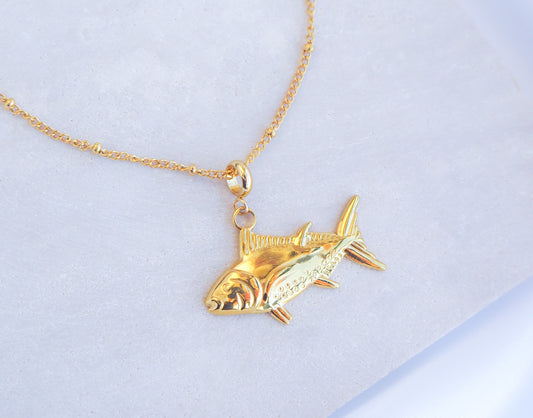 Gold Tuna Fish Necklace on stone