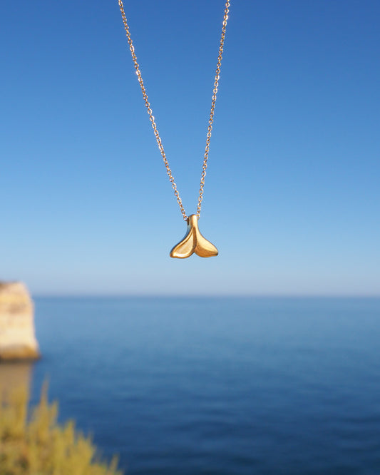 Gold Whale Tail Necklace with ocean background