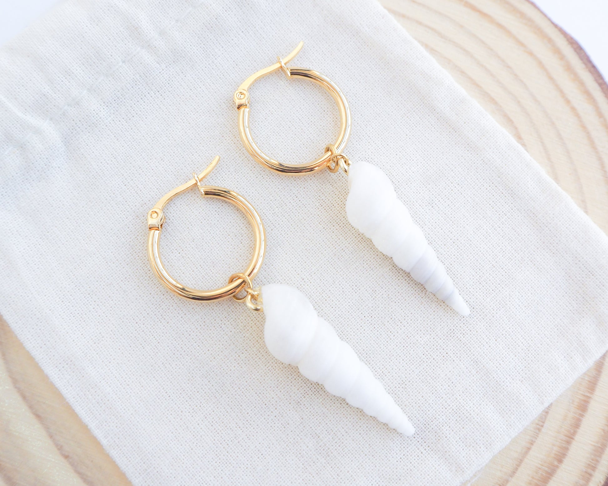 Close up of White Common Tower Shell Gold Earring Hoops on display, handpicked white tower shells from Portugal, 18k gold stainless steel shell earring hoops, seabylou 