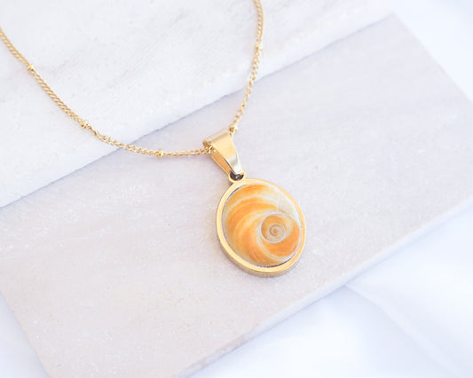 Gold Yellow Orange Shiva Eye, Eye of Saint Lucia Gold Necklace on stone displayed, 18k gold stainless steel shiva Yellow Orange eye pendant necklace, Saint Lucy Eye, operculum pendant