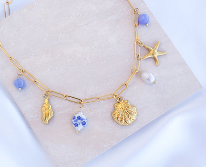 Oceanic Charm Necklace with Shells and Starfish Pendants, Freshwater Pearls and Gemstones on stone