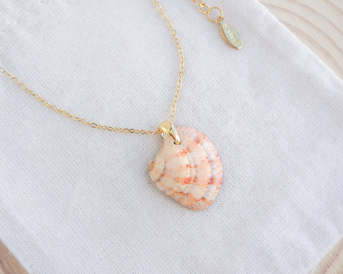 Side view of Orange Coral Venus Shell Necklace on display. Real natural venus shell handpicked from Portugal. Made with 18k gold stainless steel clasp and chain. 