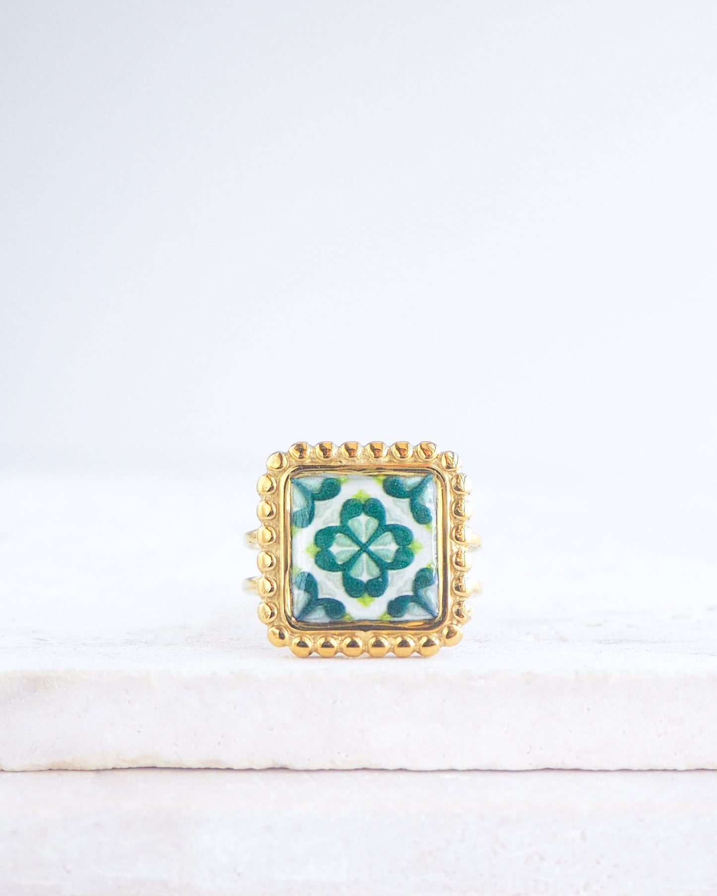 Green Gold Portuguese Tile Square Ring on stone displayed. Rings is handmade with 18k gold stainless steel and has a green floral tile pattern inspired by the Portuguese azulejos tiles. 