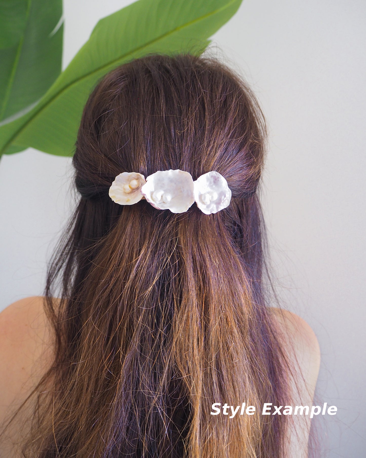 Model wearing Pearl oyster shell hair clip with pearls on in brown long hair with green plant and white background. Made with handpicked jingle shells saddle oysters from Portugal. Jingle Shell Pearl Hair clip. pearly shell Hair Clip Barrette on stone displayed, Boho Seashell Beach Clip from Portugal, Handpicked Real Shells, Seashell Hair Decoration, Bohemian Seashell Wedding Hair accessories, Coastal Christmas gift, Beach Wedding Hair