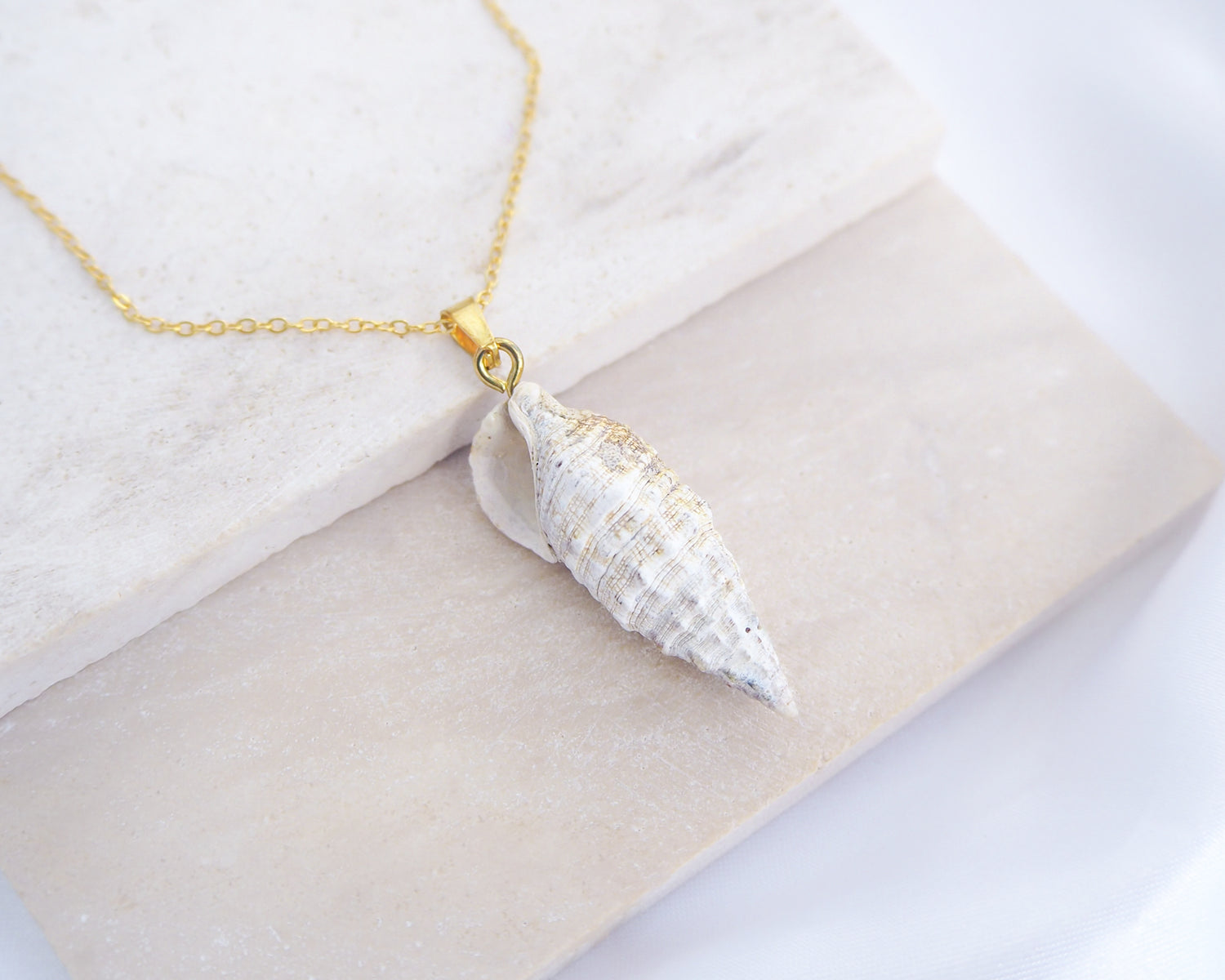 Close up of Ivory Horn Shell Necklace on stone displayed. Made with 18k gold stainless steel 