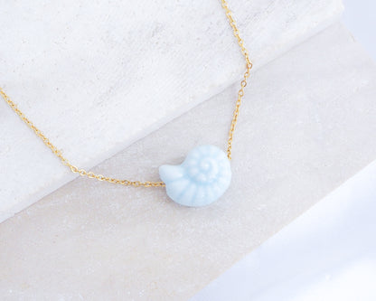 Light Blue Ceramic Seashell Nautilus Gold Necklace displayed on stone