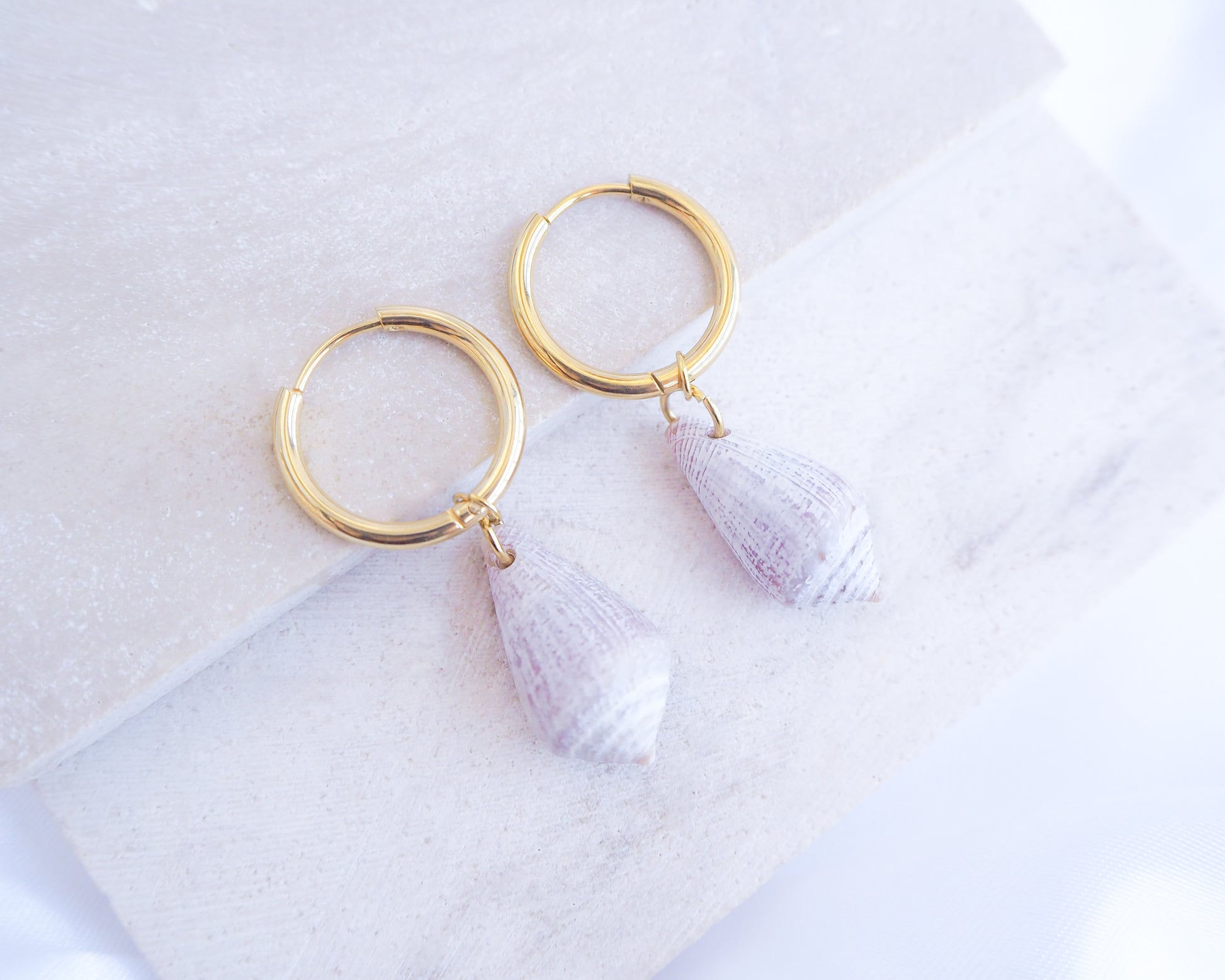 Light Mediterranean Cone Shell Gold Earring Hoops II displayed on stone, handpicked cone shells from Portugal, 18k gold stainless steel shell earring hoops, seabylou 