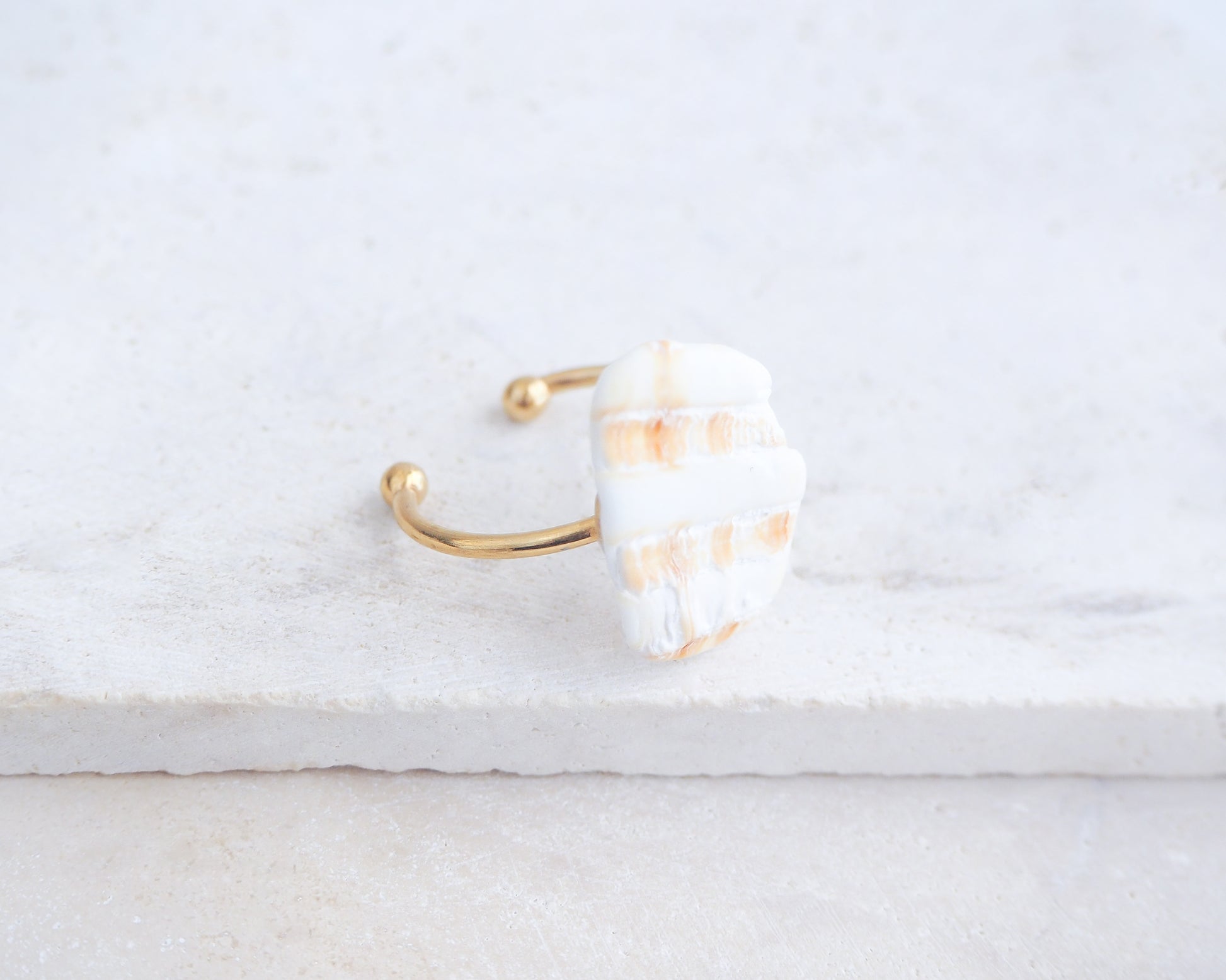 Side view of Mediterranean Cockle Shell Piece Gold Ring from Portugal on stone displayed, beach surf girl jewelry, gold ring with Portuguese cockle shell, ocean inspired beach jewelry, sunny yellow orange shell from Algarve