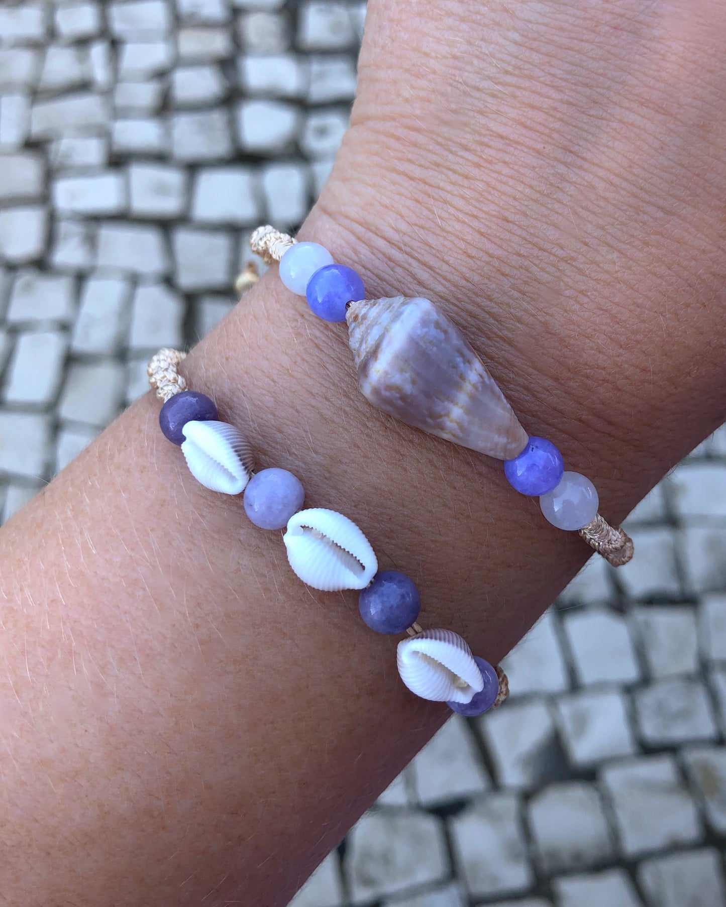 Close up of Angelite Cone Shell Bracelet and Cowrie Amethyst Bracelet on wrist. Handbraided macrame bracelet with handpicked cone shell from Portugal and gemstone. 