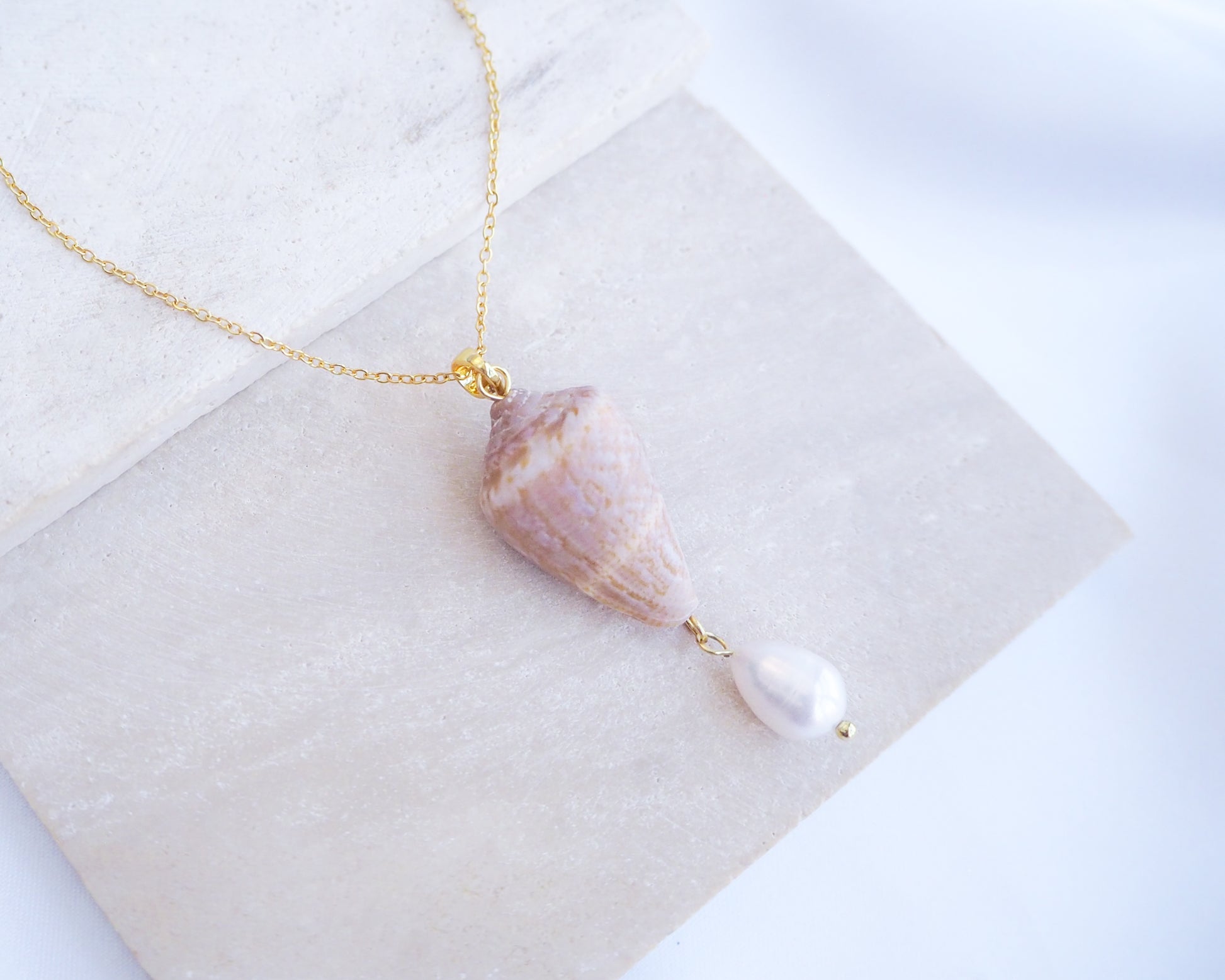 Mediterranean Cone Shell Pearl Necklace Reversed from Portugal on stone displayed, handpicked cone shell from Algarve, Freshwater pearl and 18k gold stainless steel chain