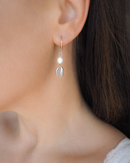 Model wearing Silver Hoop Earrings with Cowrie Shells and Freshwater Pearls in ear side view. 