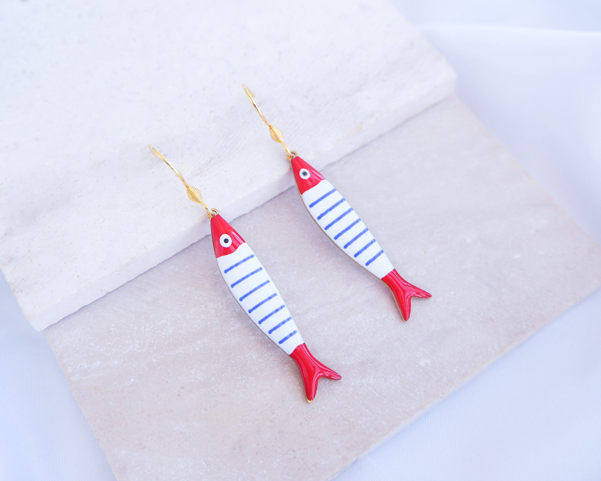 Nautical Striped Sardine Fish Earrings with 14k gold stainless steel earring hooks displayed on stone, Red Blue White Striped Fish Pendant, Beautiful gift for Portugal lovers or holiday memory, coastal jewelry from Portugal